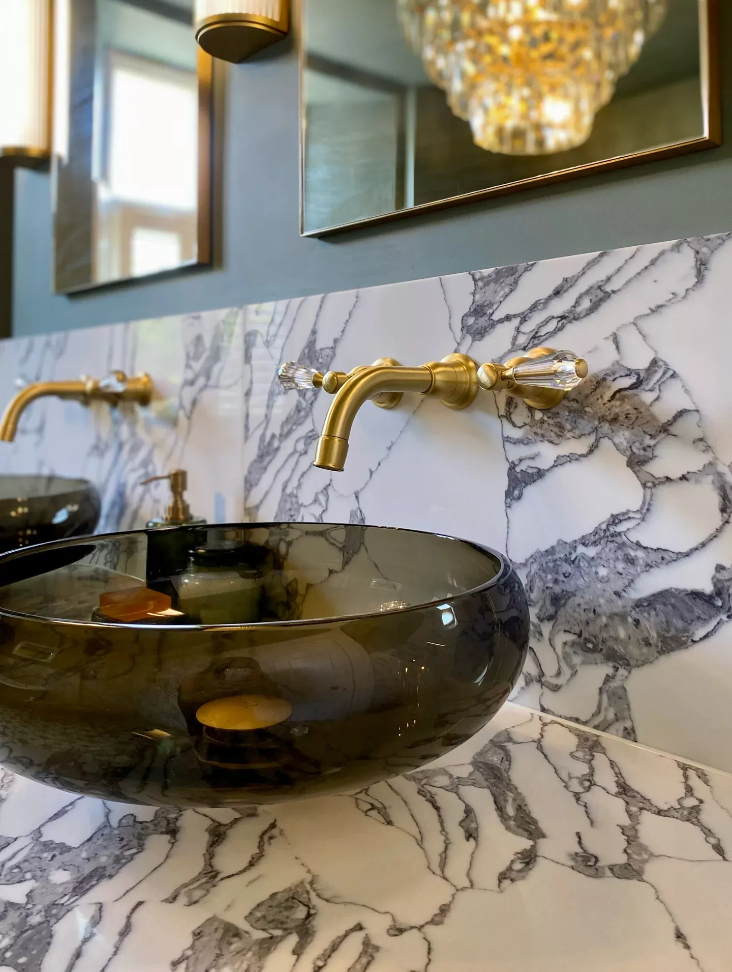 Dark glass vessel basin beneath a brass wall-mounted tap