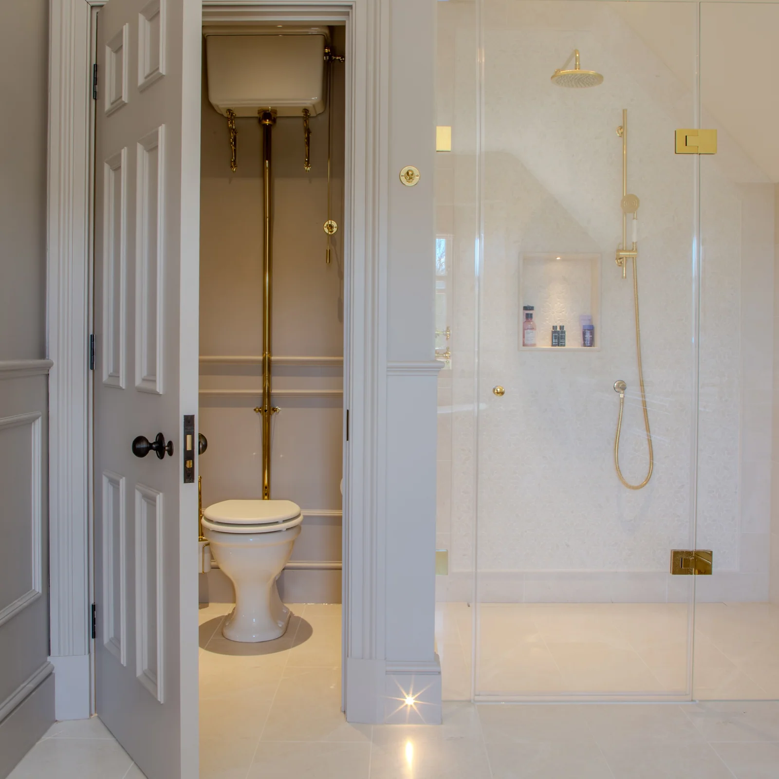 Walk-in shower with brass fittings beside a traditional toilet