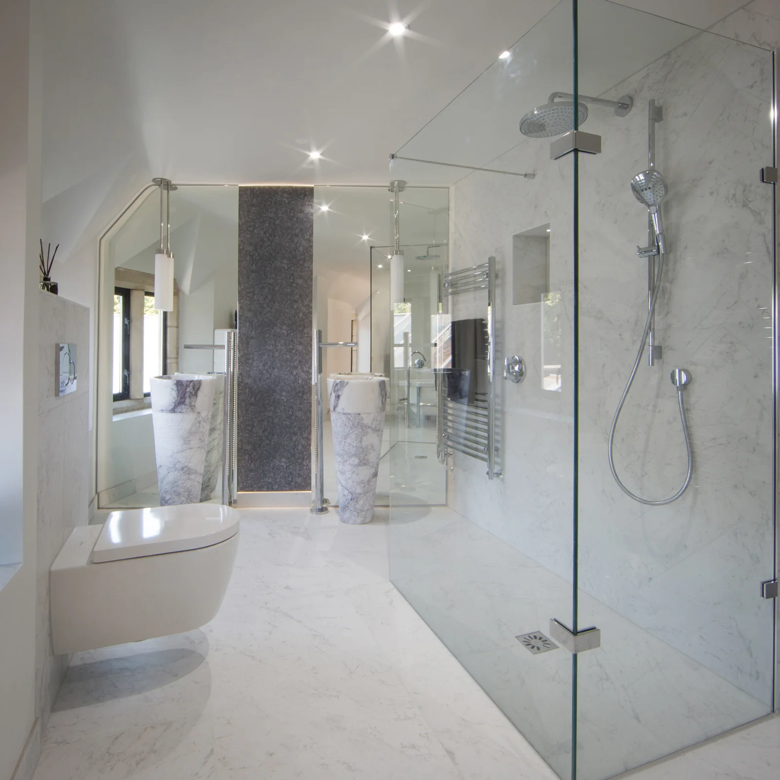 Glass shower enclosure and pale tiled walls in the luxurious en-suite
